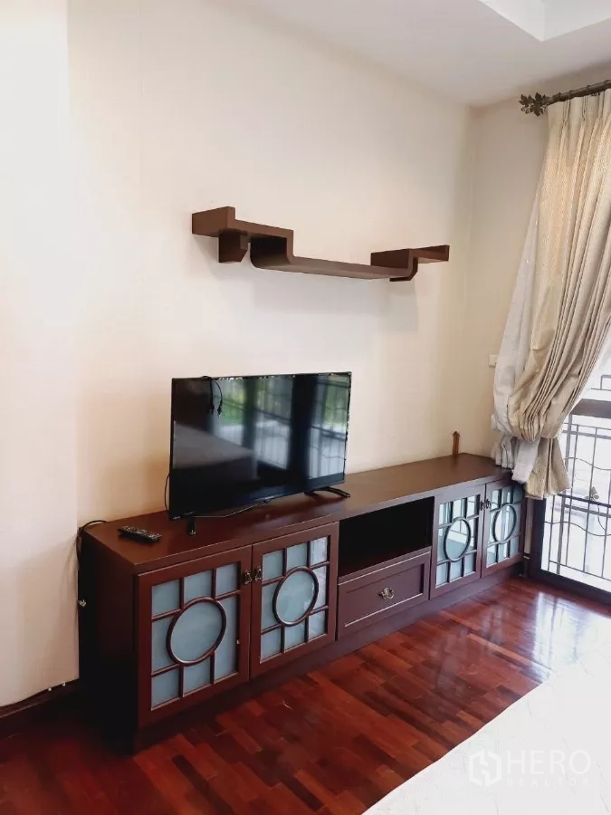 独立式住宅 出租或出售在Mueang Nonthaburi, Nonthaburi - 卧室内的定制电视柜与壁架，木地板、窗帘齐全。