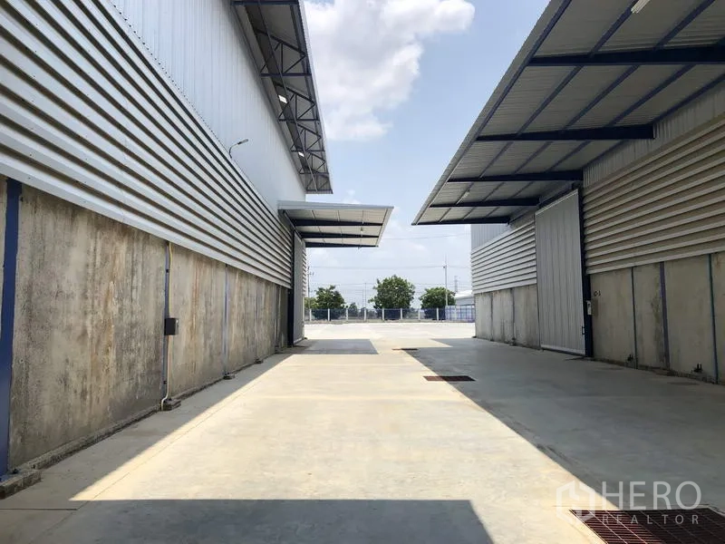 货栈 出租在Lat Lum Kaeo, Pathum Thani - 仓库之间的通道，带雨棚的装卸区和宽敞的混凝土道路。