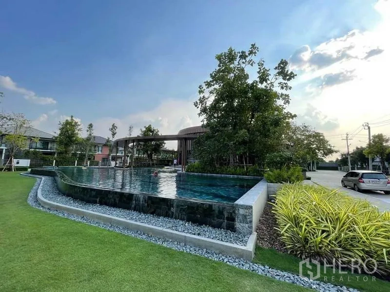 บ้าน ขายในPak Kret, Nonthaburi - สระว่ายน้ำอินฟินิตี้สไตล์รีสอร์ท ข้างสนามหญ้าและต้นไม้ในโครงการ