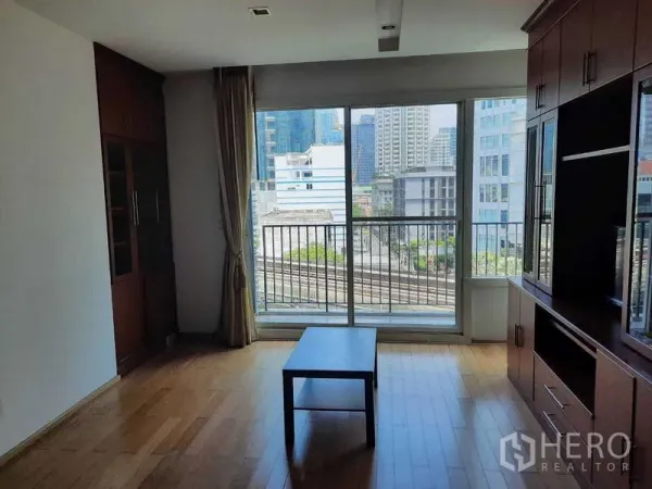 Condominium for rent in Khlong Toei, Bangkok - Bright living room with floor-to-ceiling windows, balcony, and city skyline view.
