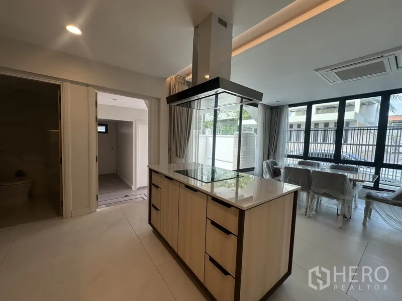 联排别墅 出租在Watthana, Bangkok - 带顶吸的中岛厨房，连通餐区与推拉落地门露台