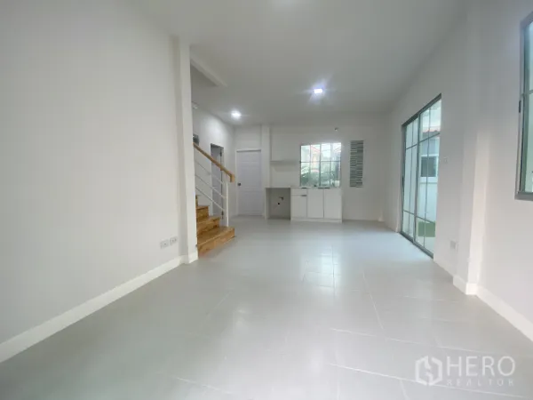 บ้าน ขายในNonthaburi - พื้นที่นั่งเล่นรับประทานอาหารกว้าง ปูกระเบื้อง บันได และประตูกระจกออกสู่สวน.