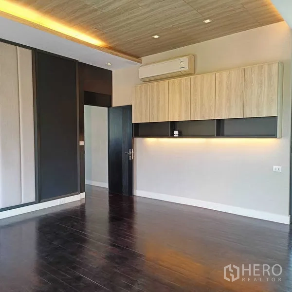独立式住宅 出租或出售在Mueang Nonthaburi, Nonthaburi - 采光明亮的卧室，深色木地板与内置柜、天花氛围灯。