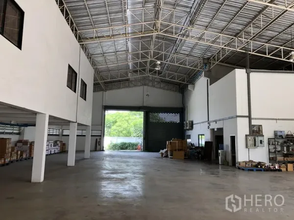 Factory for rent or sale in Lat Lum Kaeo, Pathum Thani - Warehouse hall facing a large loading roller door with storage areas and ceiling lights.