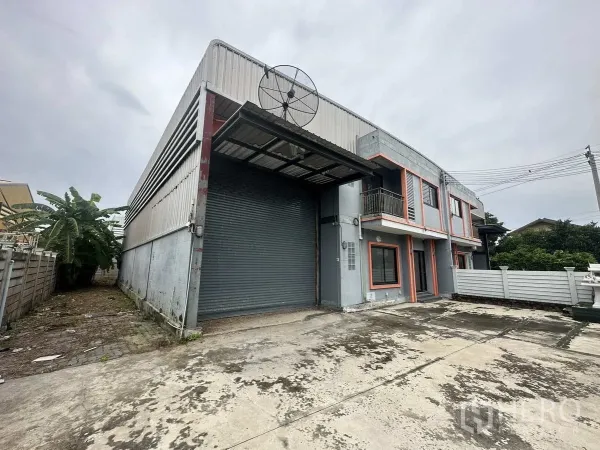 Warehouse for rent or sale in Bang Yai, Nonthaburi - Angled view of the warehouse showing covered loading bay and metal roller door with ample driveway.