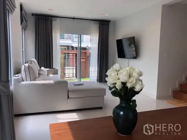 Detached House for rent in Suan Luang, Bangkok - Bright living room with L-shaped sofa, sliding glass doors and wall-mounted TV.