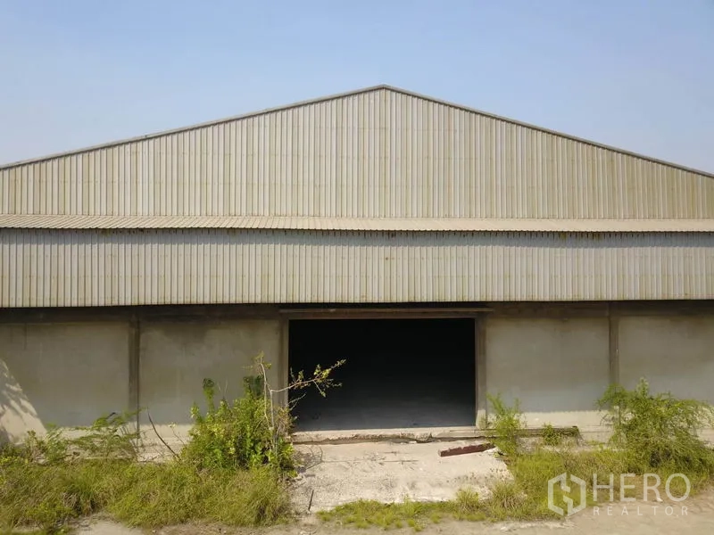 Factory for sale in Samut Prakan - Front facade of the corrugated metal factory building with a large loading entrance.