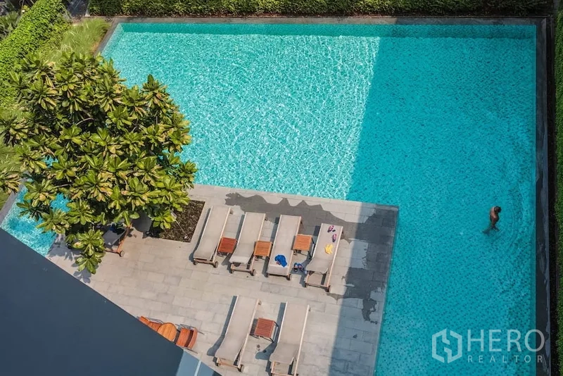 公寓 出租在Watthana, Bangkok - 室外游泳池配躺椅与日光平台，园景绿意环绕。