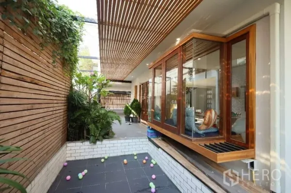 独立式住宅 出租在Lat Phrao, Bangkok - 郁郁葱葱的天井，木格栅顶棚与玻璃转角飘窗座