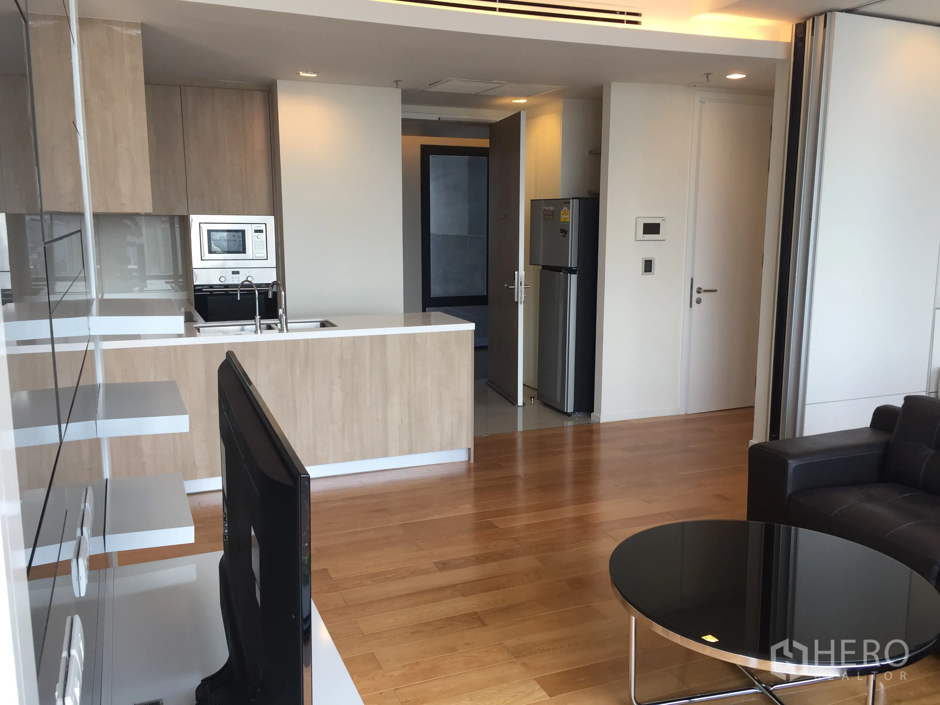 Condominium for rent in Ratchathewi, Bangkok - Open-plan living area with modern kitchen island, built-in appliances, and wooden floors.