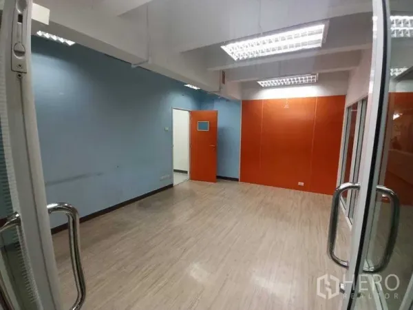 Office Space for rent in Ratchathewi, Bangkok - Private office with blue wall, orange feature panel and a glass door, ideal for a meeting or team room.