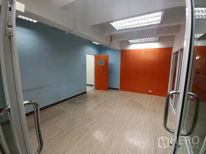 Office Space for rent in Ratchathewi, Bangkok - Private office with blue wall, orange feature panel and a glass door, ideal for a meeting or team room.
