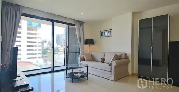 Condominium for rent or sale - Another angle of the living room showing balcony doors, sofa and round coffee table.