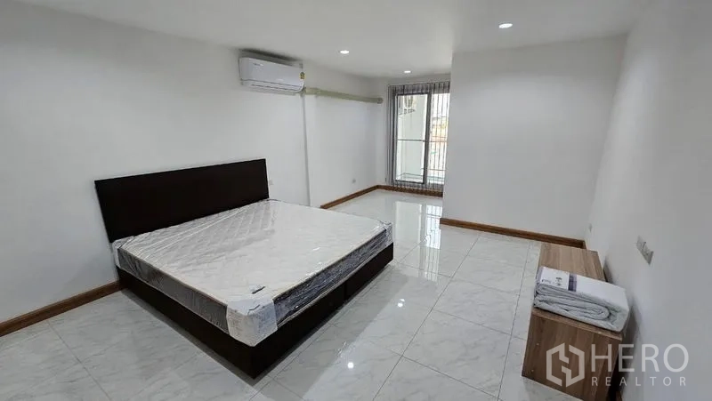 สำนักงานที่บ้าน ให้เช่าในBang Na, Bangkok - ห้องนอนกว้างมีเตียง เครื่องปรับอากาศ และประตูออกสู่ระเบียงเล็ก