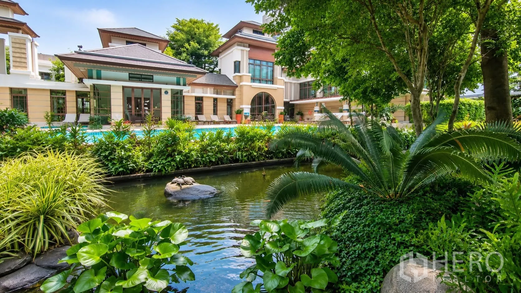 独栋房屋 for rent in Watthana, Bangkok - 园林水景与绿化前方为带泳池的会所式建筑。