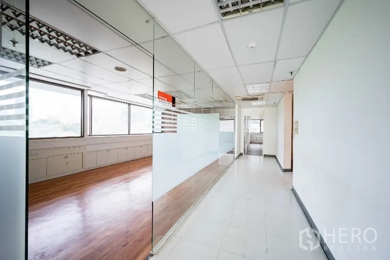 Office Space for rent in Pathum Wan, Bangkok - Bright office corridor with full-height glass partitions, frosted panels, and an adjacent wood-floor meeting room with large windows.