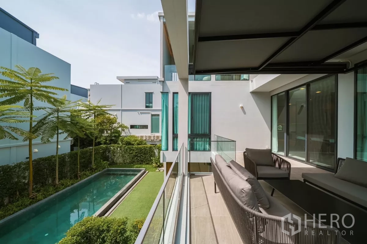 Detached House for rent or sale in Saphan Sung, Bangkok - Balcony seating overlooking a lap pool, trimmed lawn and minimalist neighboring homes.