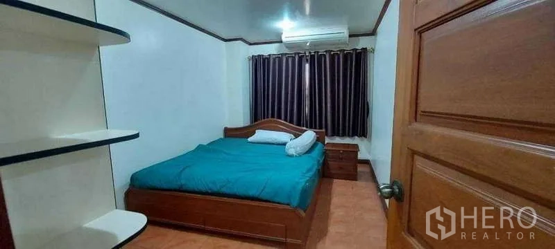 Condominium for rent in Khlong Toei, Bangkok - Cozy secondary bedroom with teal bedding, wall shelves, dark curtains and air conditioning.