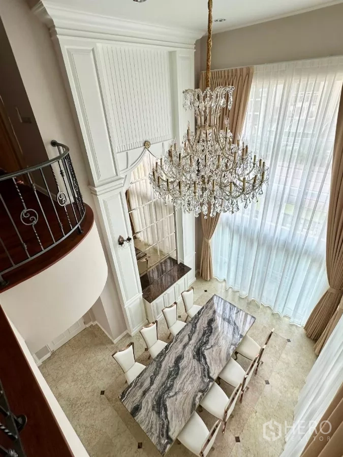 Townhouse for rent in Bang Kho Laem, Bangkok - Overhead view of crystal chandelier above marble dining table and double-height windows
