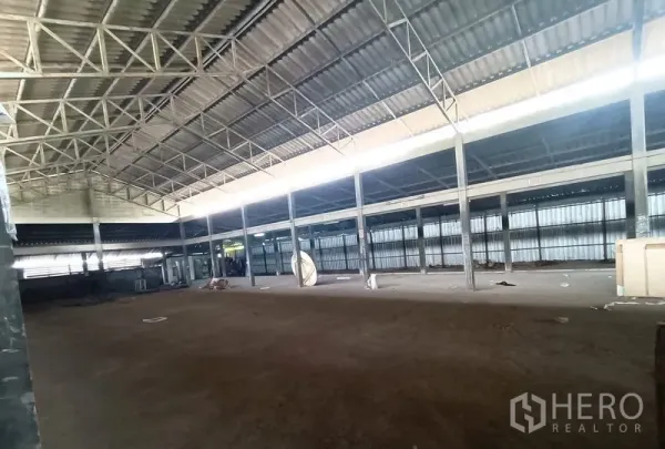 Warehouse for rent in Saphan Sung, Bangkok - Side view of warehouse hall showing steel columns, ventilated wall panels, and wide open space.