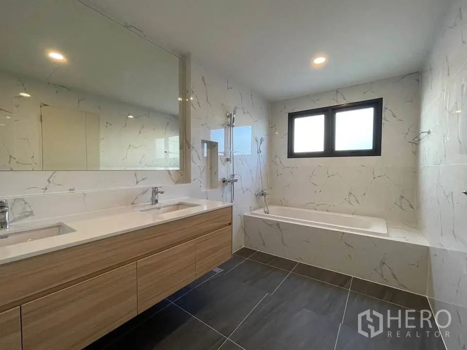 Detached House for rent or sale in Bang Phli, Samut Prakan - Bathroom with double vanity, bathtub, and marble-effect wall tiles.