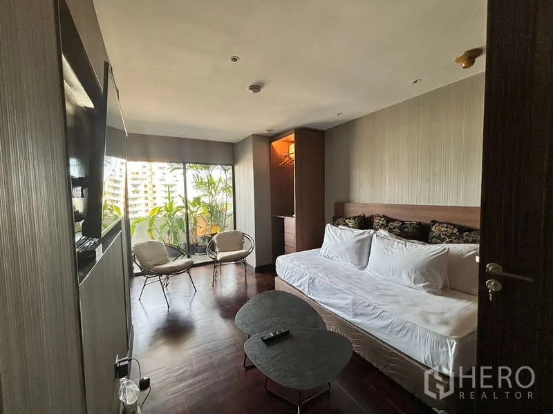 Condominium for rent in Watthana, Bangkok - Second bedroom with daybed, seating and sliding doors to leafy balcony.
