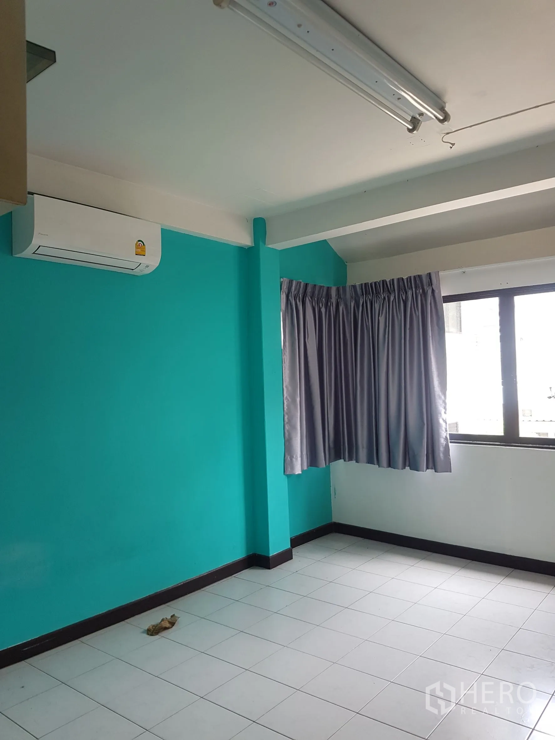 Home Office for sale in Khlong Toei, Bangkok - Air-conditioned room with teal wall and tiled floor.