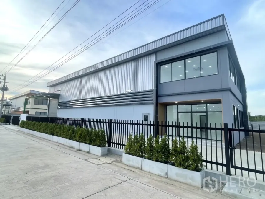 Factory for rent or sale in Bang Yai, Nonthaburi - New modern factory with glass-front office, black fence and wide concrete access road.