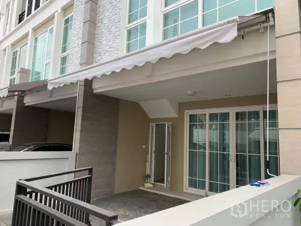 Townhouse for rent in Bang Na, Bangkok - Front row of contemporary townhouses with awnings and gated carports
