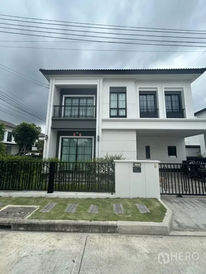 独立式住宅 出租在Khlong Sam Wa, Bangkok - 现代两层独栋别墅外观，带阳台、前庭草坪与围栏车道