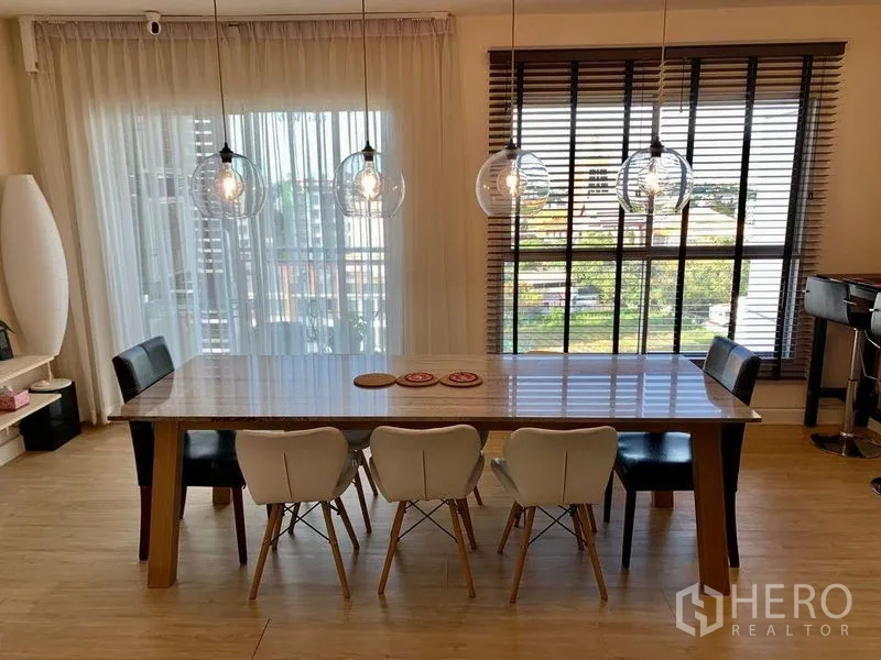 公寓 出租在Bang Na, Bangkok - 采光充足的餐厅，整面窗与纱帘，三盏吊灯照亮餐桌。