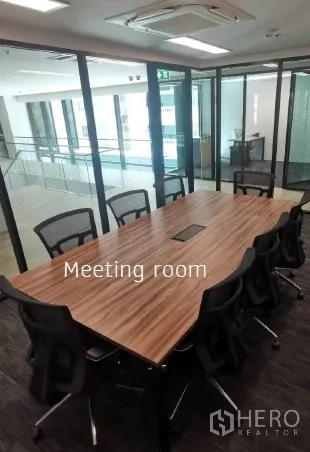 Office Space for rent in Khlong Toei, Bangkok - Glass-walled meeting room with a long wood conference table, mesh chairs, and ceiling air-conditioning in a modern office.