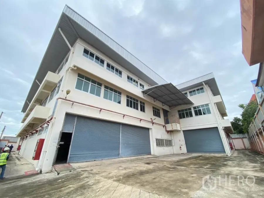 Factory for rent in Khlong Toei, Bangkok - Front facade of a multi-storey factory with large roller doors.