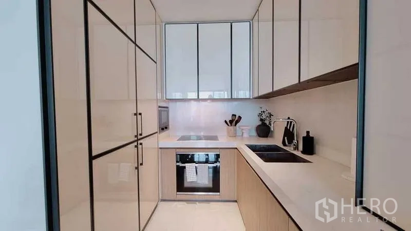 Condominium for sale - Compact modern kitchen with integrated appliances and ample storage.