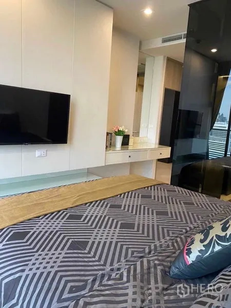Condominium for sale in Pathum Wan, Bangkok - Bedroom angle showing TV wall, vanity and glass partition.