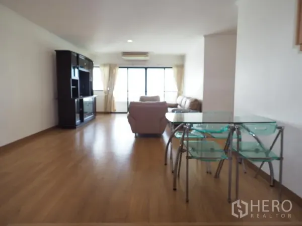 Condominium for rent in Sathon, Bangkok - Bright open-plan living and dining area with wood floors, glass table, beige sofas and sliding doors to a balcony in Sathon, Bangkok.