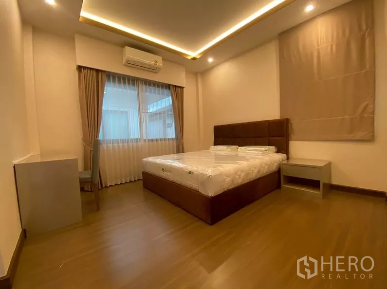 独立式住宅 出租在Prawet, Bangkok - 客卧配软包床、窗户与柔和天花灯。