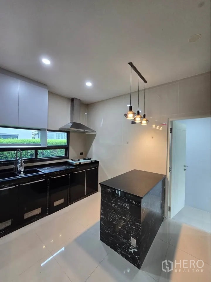 Detached House for rent in Bang Kapi, Bangkok - Full view of modern kitchen with black counters and range hood.