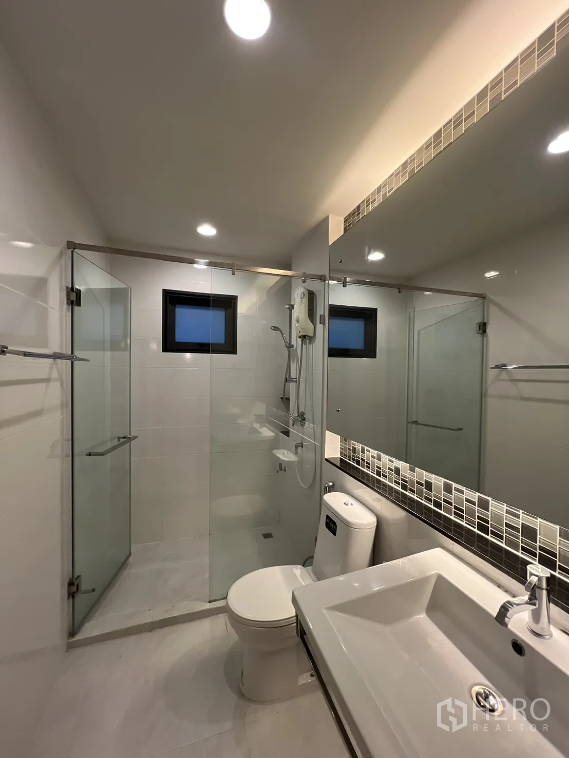 Detached House for rent or sale in Bang Kapi, Bangkok - Shared bathroom with glass shower enclosure and long mirror.