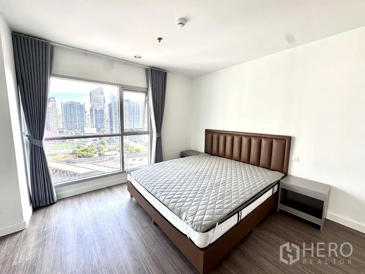 คอนโด for rent in Huai Khwang, Bangkok - ห้องนอนอีกห้องพร้อมหน้าต่างกว้าง เตียง โต๊ะข้าง ผ้าม่าน และวิวสกายไลน์