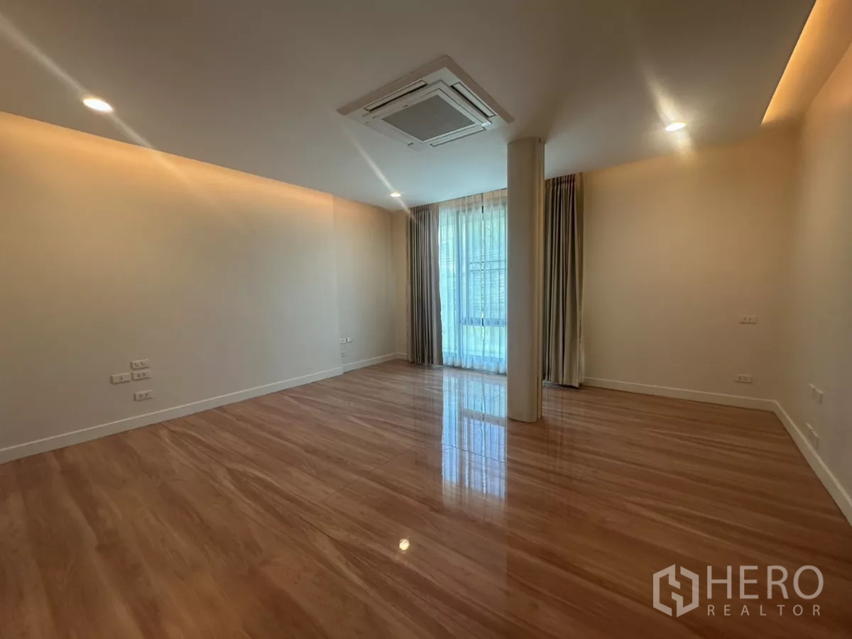 联排别墅 出租在Watthana, Bangkok - 宽敞主卧，落地窗帘与木地板。