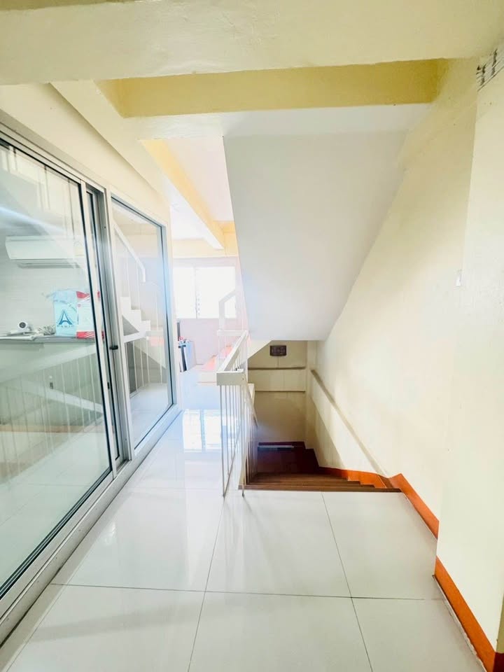 Shophouse for rent in Phra Khanong, Bangkok - Stair landing with white tiles, glass partition and wooden steps leading down.