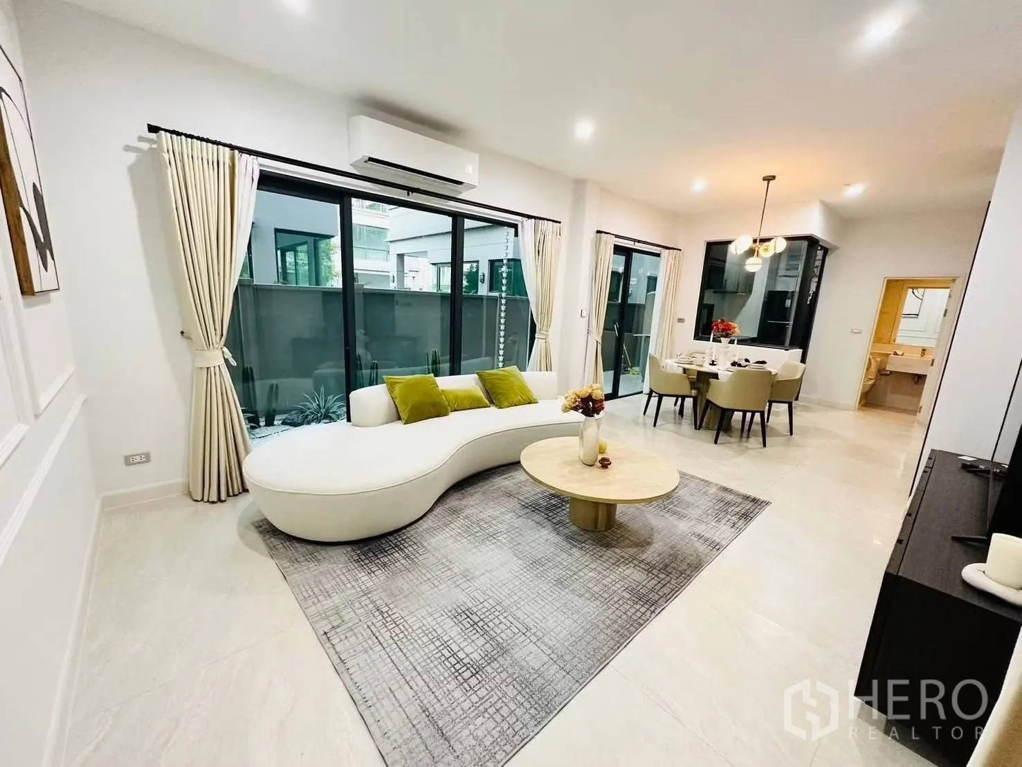 联排别墅 for rent in Suan Luang, Bangkok - 客厅通过大推拉门眺望庭院，旁接餐区。