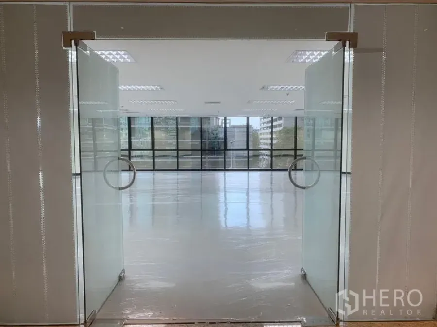 Office Space for rent in Bang Rak, Bangkok - Frosted glass double doors opening to a modern, sunlit office with wall‑to‑wall windows.