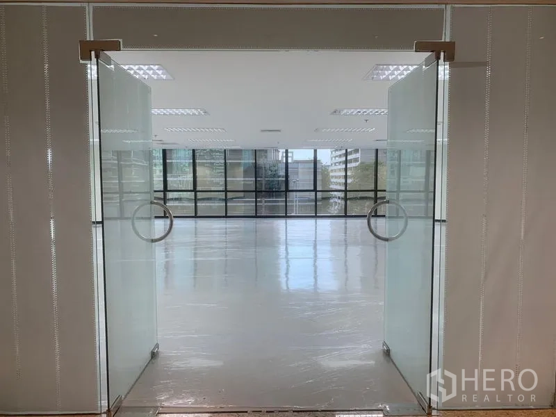 Office Space for rent in Bang Rak, Bangkok - Frosted glass double doors opening to a modern, sunlit office with wall‑to‑wall windows.