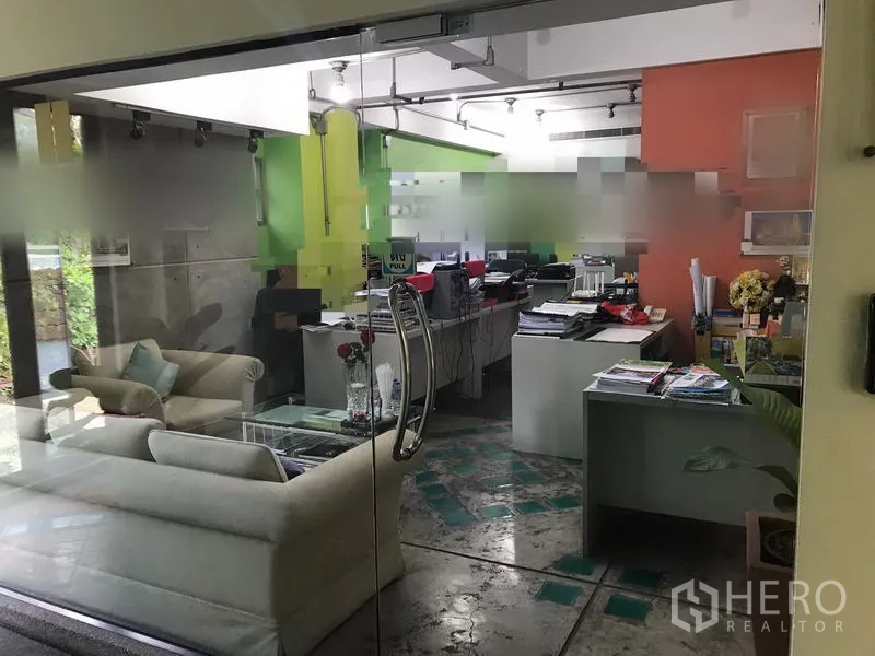 办公空间 出租在Watthana, Bangkok - 明亮的办公内景，玻璃门、休闲区、绿色点缀墙与轨道灯。