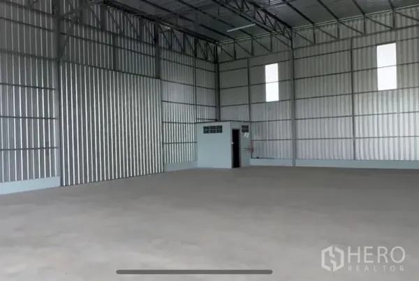 Warehouse for rent in Lam Luk Ka, Pathum Thani - Clean interior of the warehouse highlighting skylight panels, steel trusses and corner utility room.