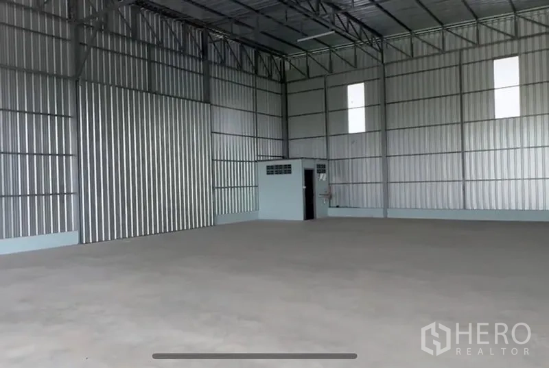 Warehouse for rent in Lam Luk Ka, Pathum Thani - Clean interior of the warehouse highlighting skylight panels, steel trusses and corner utility room.