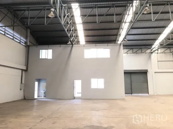 Factory for rent in Pathum Thani - Interior view showing a two-storey office block, wide roller shutter and open production area.