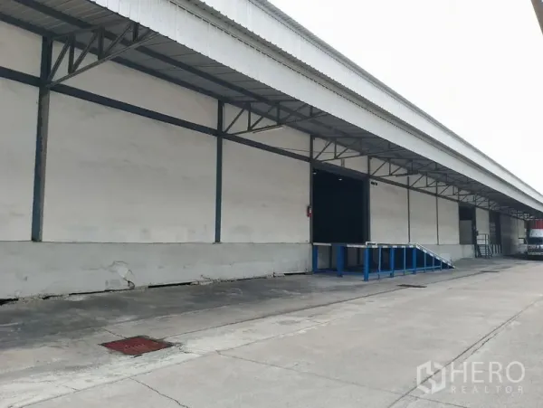 คลังสินค้า ให้เช่าในBang Phli, Samut Prakan - ด้านหน้าโกดังยาว มีชายคาพร้อมพื้นที่ขนถ่ายและเลนสำหรับรถบรรทุก